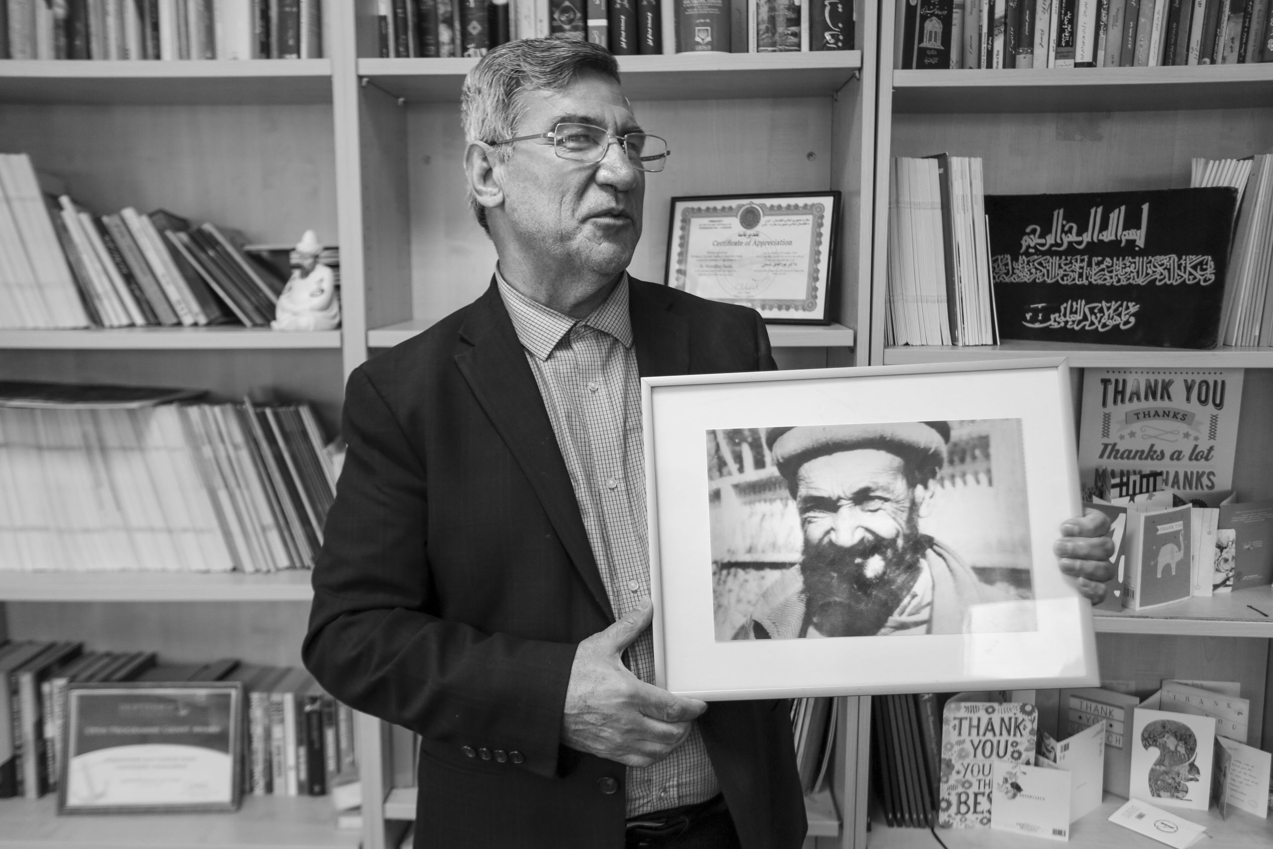 Dr Nasimi poses in his office holding a photograph of his father, an educator influencer who played a key role in getting children back into school back in Afghanistan.