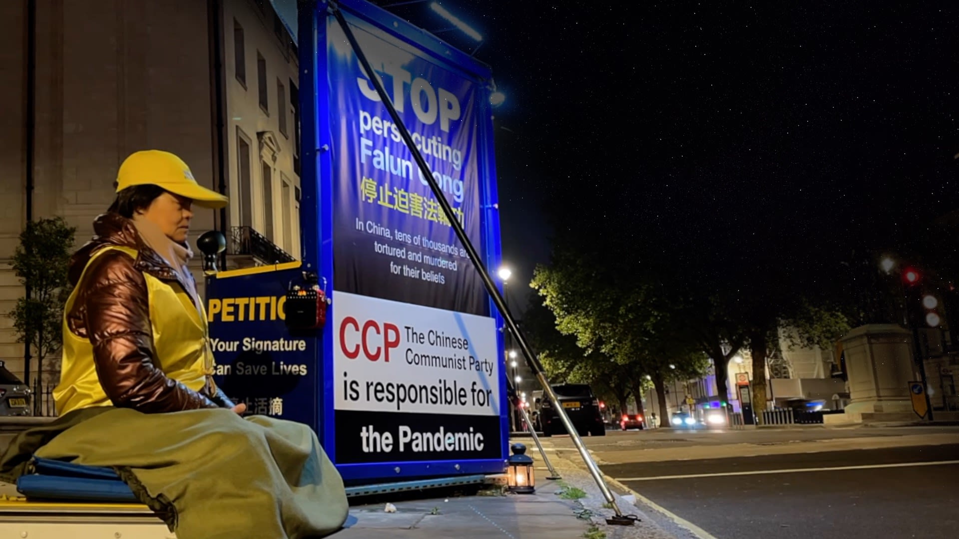 Protestor sitting down outside Chinese Embassy at night